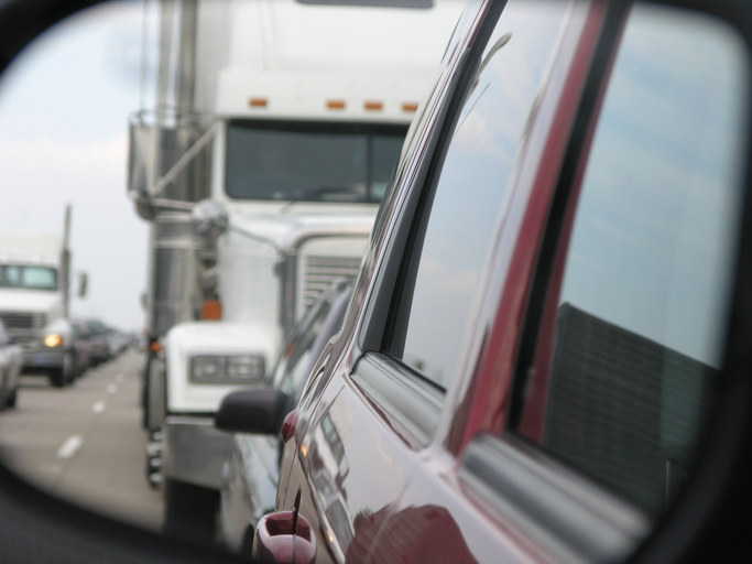 View of a truck through a rear-view mirror of a car - can more than one party be responsible in truck accidents in California?